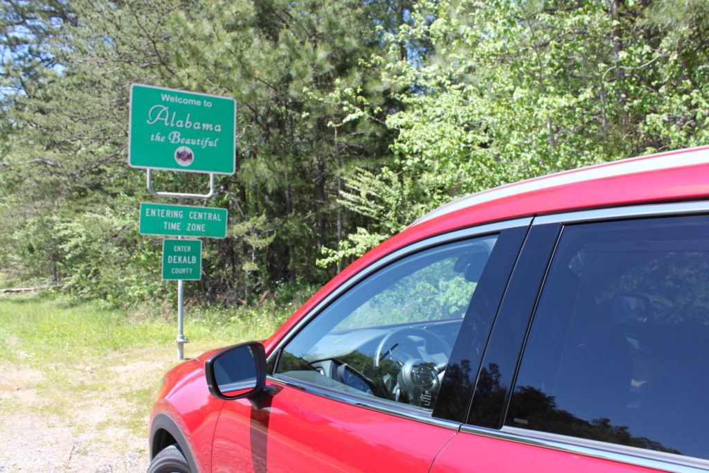 red car in front of sign at Alabama state line